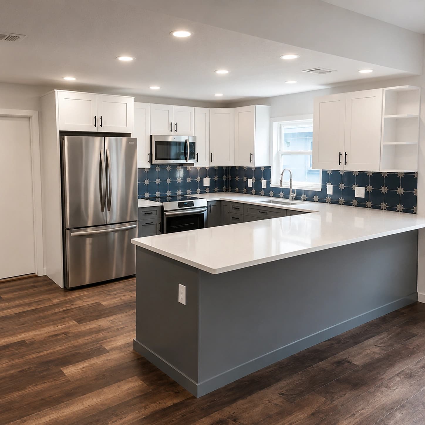 Remodeled kitchen with gray shaker cabinets, white upper cabinets, quartz peninsula, and blue tile backsplash in Brandon, FL