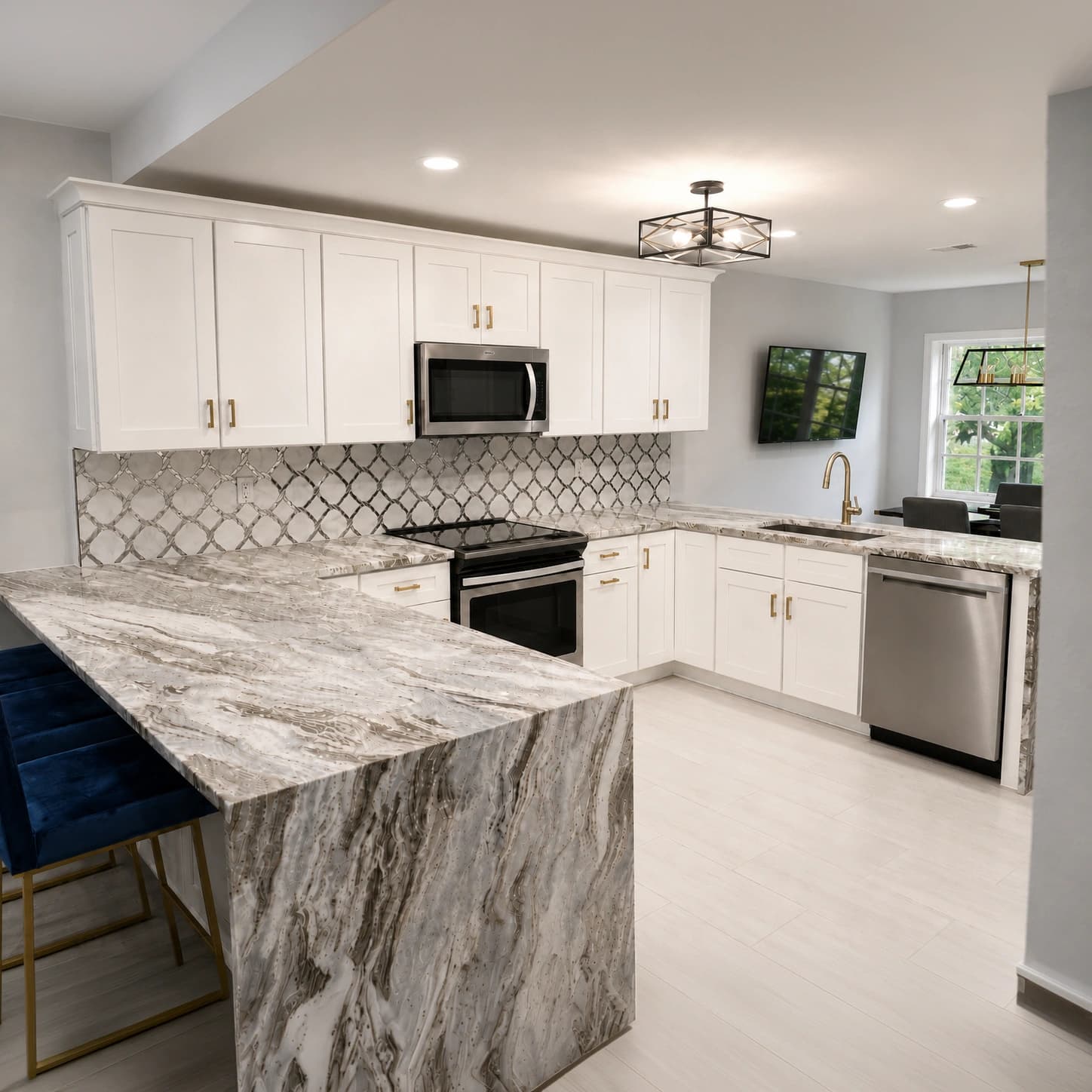 Luxury kitchen remodel with white shaker cabinets, waterfall stone island, patterned backsplash, and stainless steel appliances in Tampa, FL