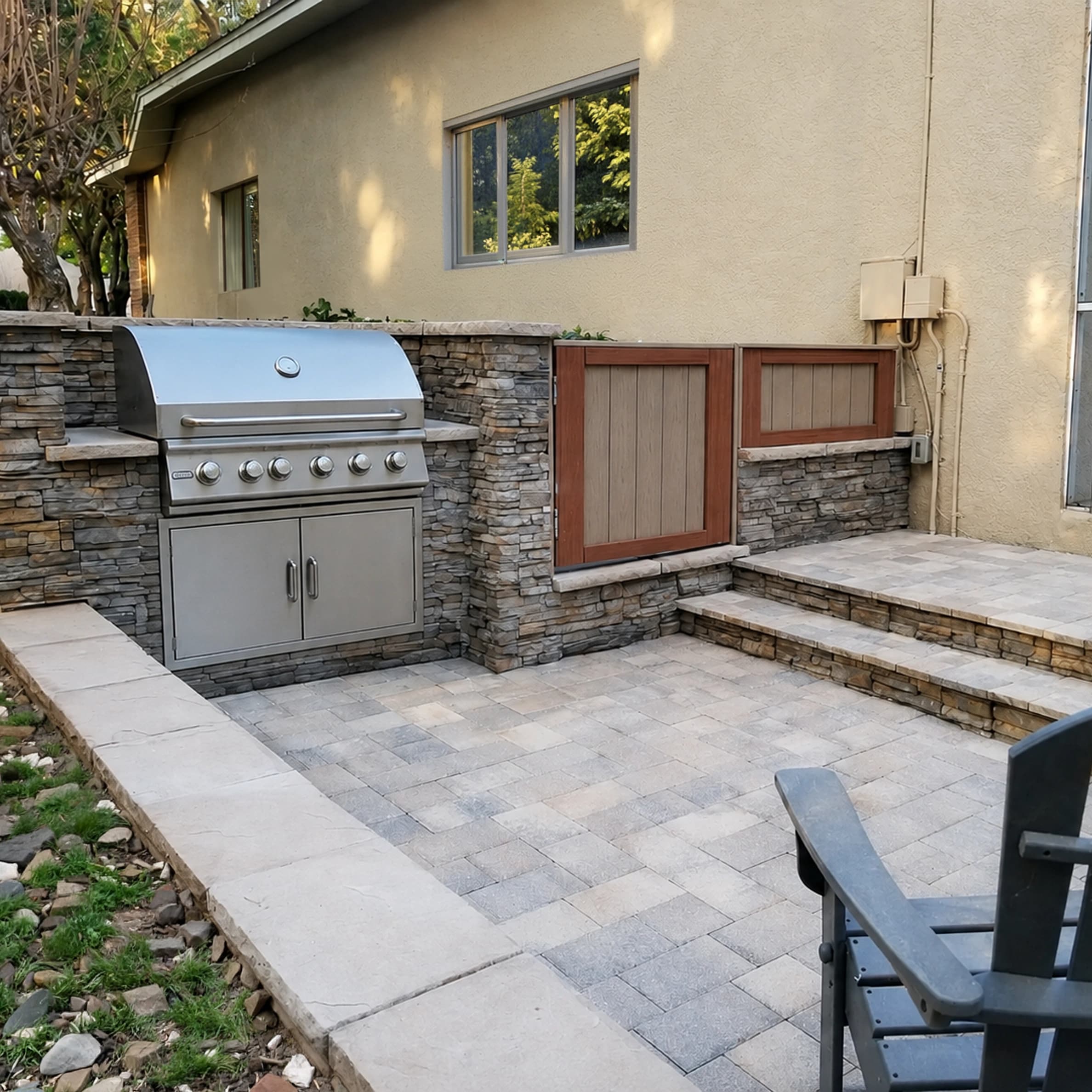 Custom stone outdoor kitchen with built-in stainless steel grill, paver patio, and stone seating walls in Riverview, FL